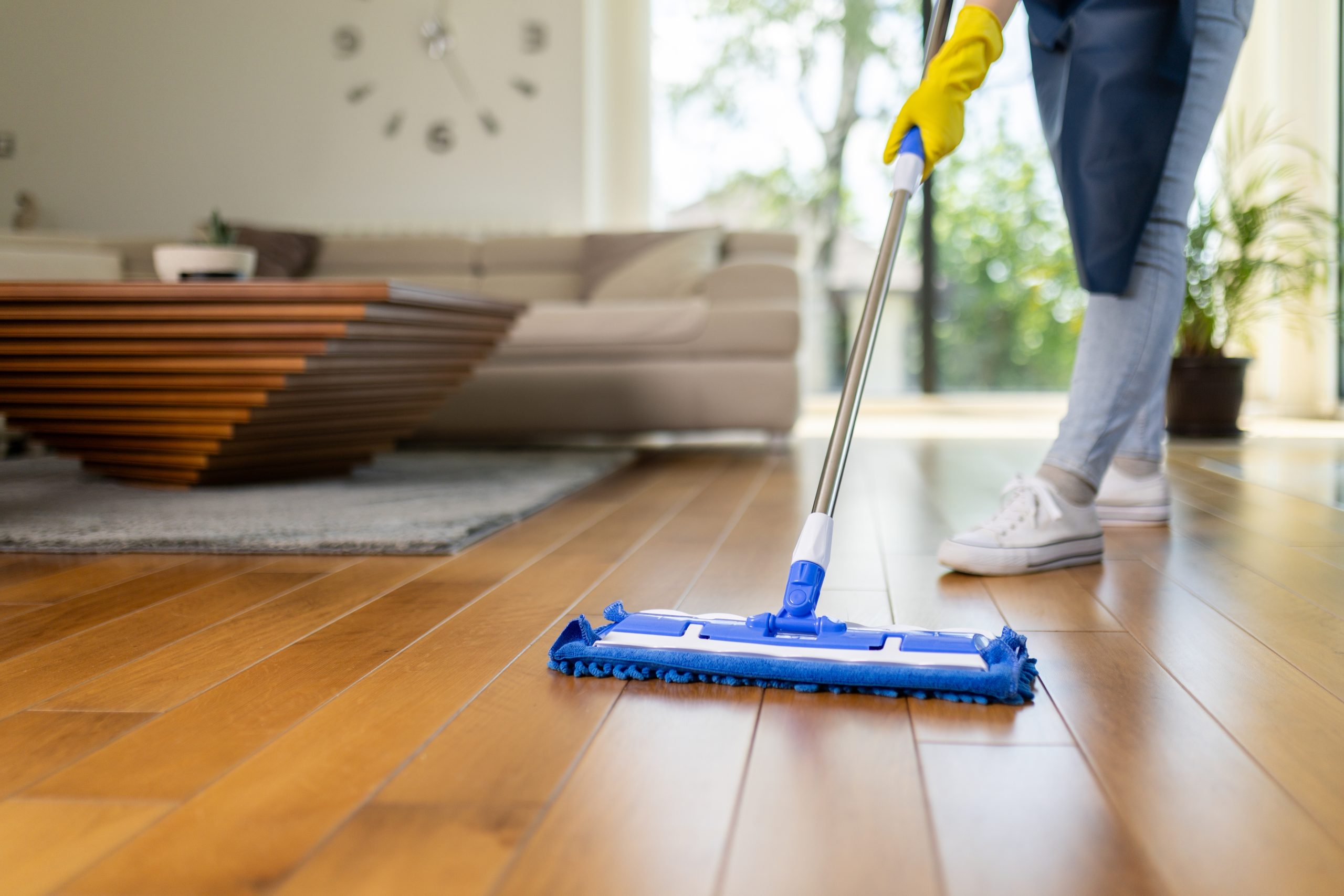 Microfibre mop cleaning a newly finished solid oak plank hardwood floor after the Sand Floors process, showing gentle aftercare in a living room.
