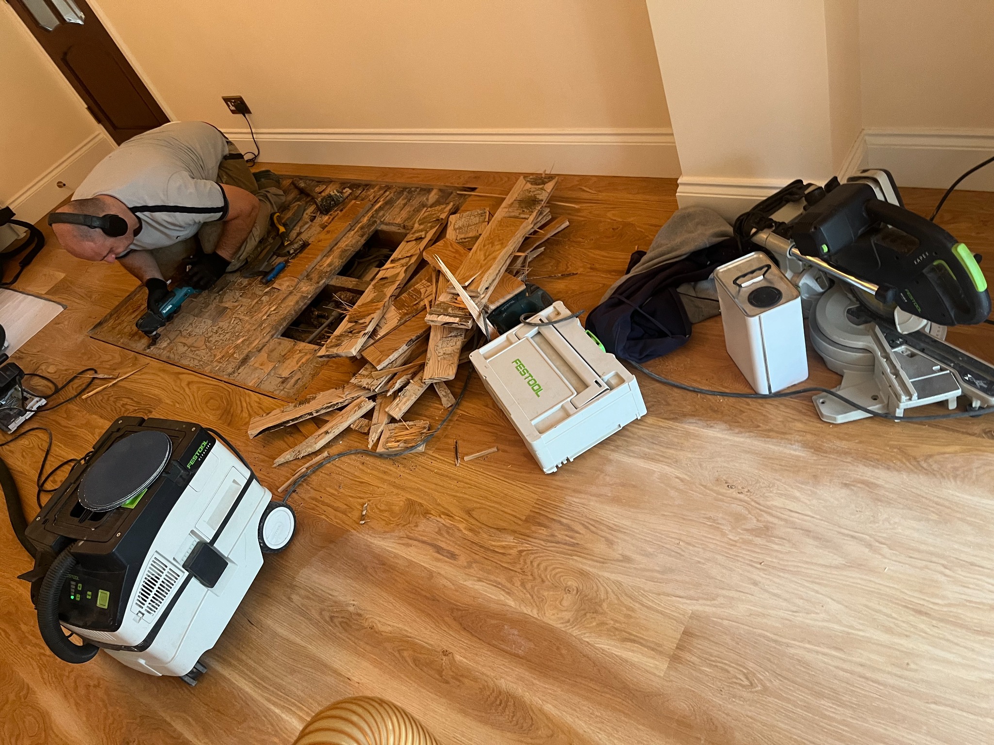 Technician replacing damaged boards on a European oak plank hardwood floor before the Sand Floors process, using dust-extraction tools and preparing the subfloor.