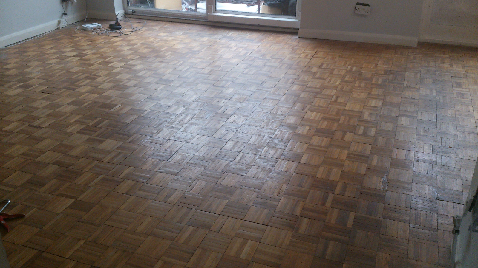Before Wood Floor Sanding on a tired finger block parquet wood floor, showing worn, dull and uneven blocks across a living room.