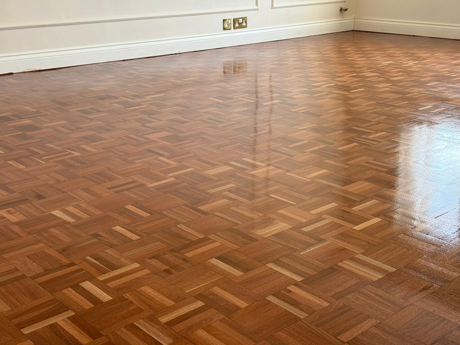 Wood Floor Sanding on a finished mosaic parquet wood block floor, restored to a smooth, high-gloss finish in a large living room.