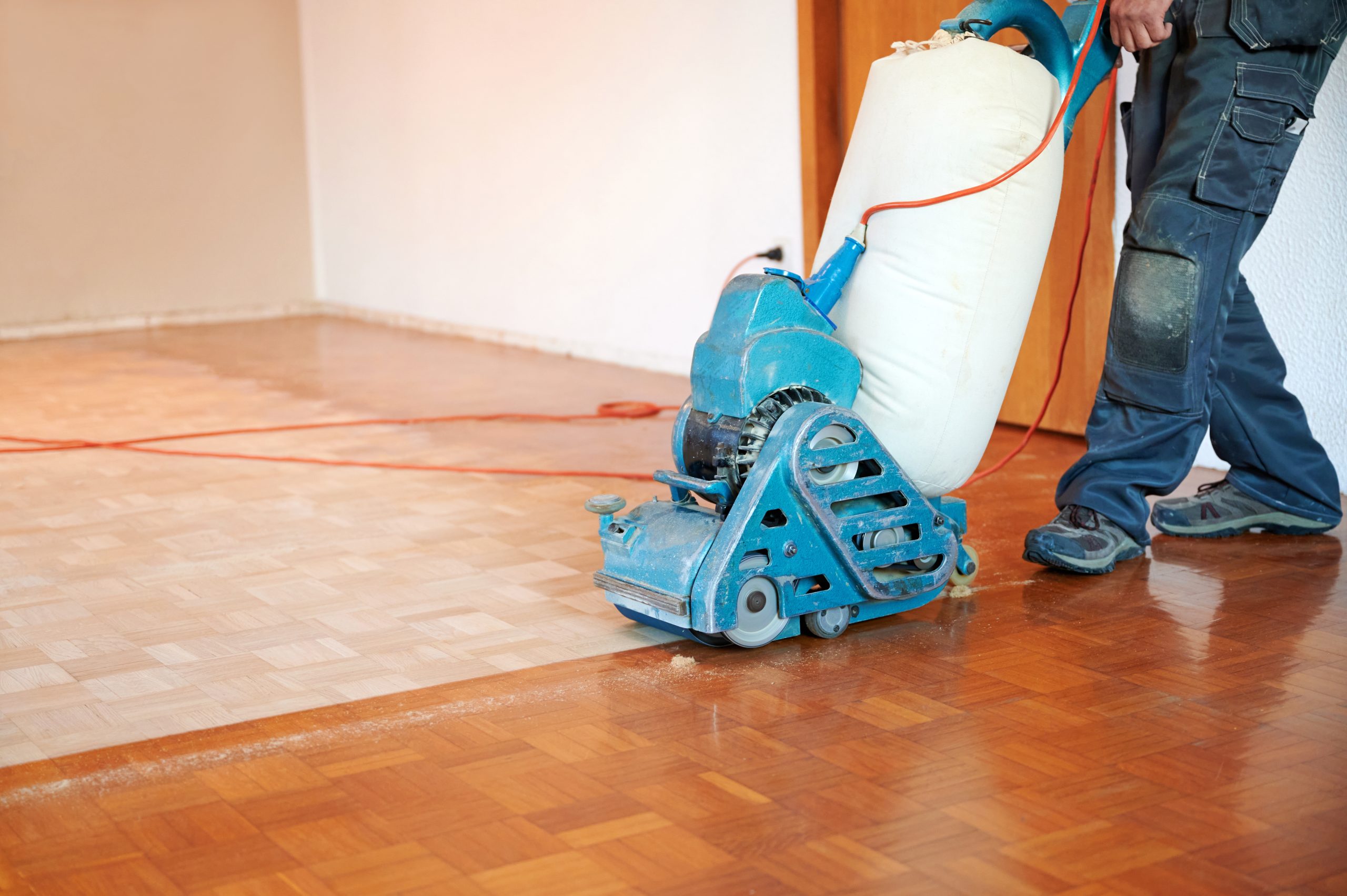 Professional Wood Floor Sanding on mosaic parquet wood block flooring with a drum sander in a living room.